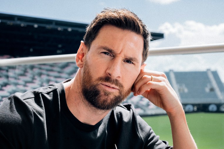 Lionel Messi with the stadium and field behind him.