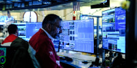 A trader looks at computer screens at his desk
